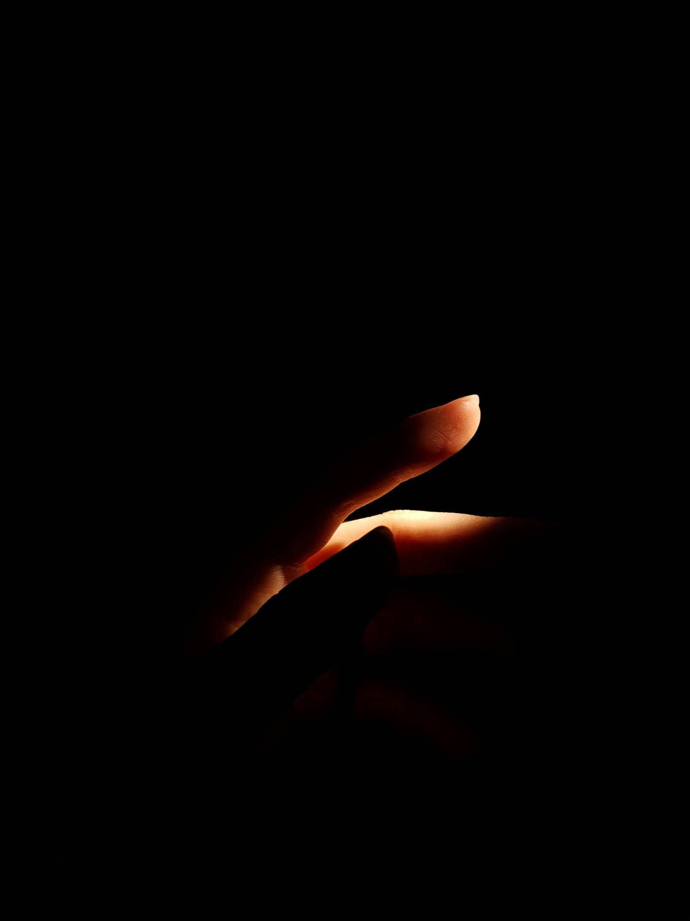 A fingertip lit by a single warm light on black, about to tap send